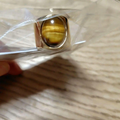 A gold ring with a spherical design featuring onyx and tiger's eye stones.