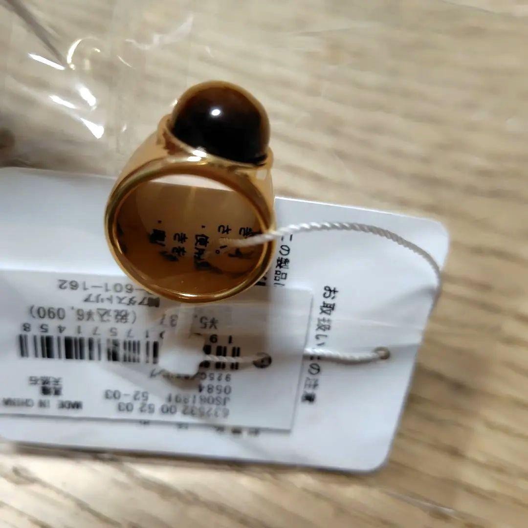A gold ring with a spherical design featuring onyx and tiger's eye stones.