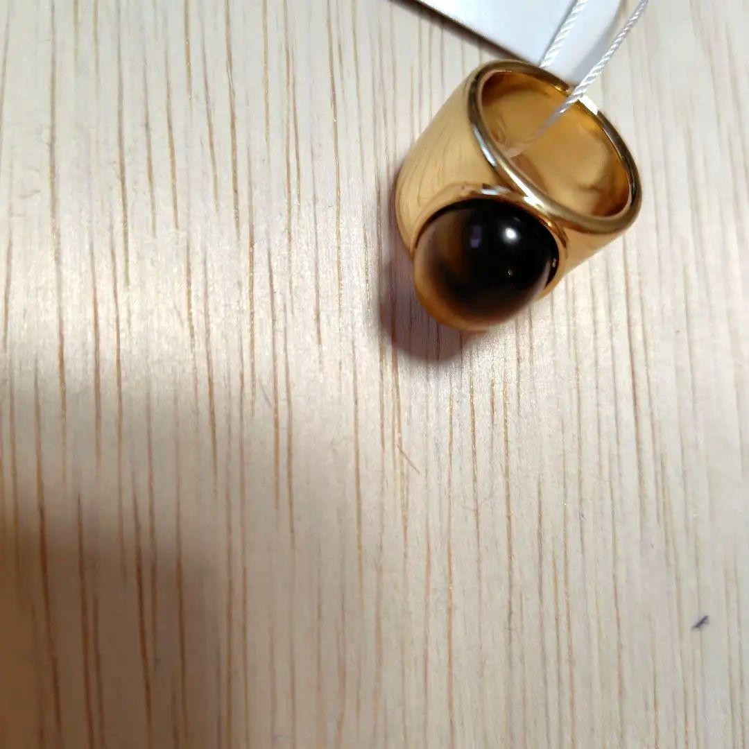 A gold ring with a spherical design featuring onyx and tiger's eye stones.