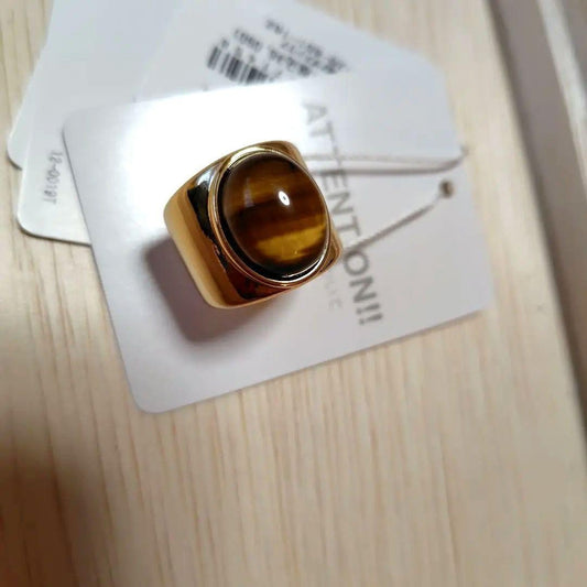 A gold ring with a spherical design featuring onyx and tiger's eye stones.