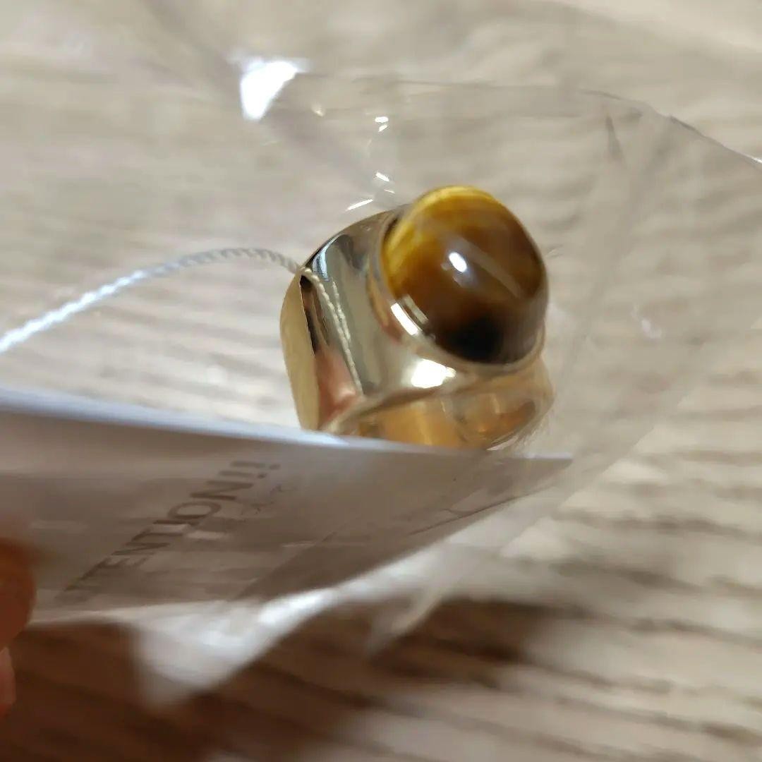 A gold ring with a spherical design featuring onyx and tiger's eye stones.