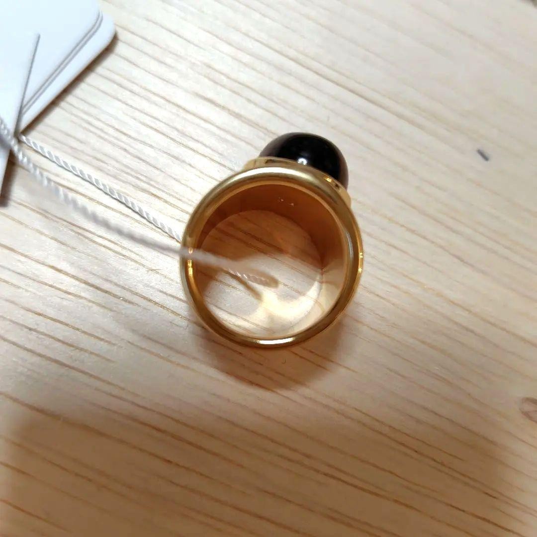 A gold ring with a spherical design featuring onyx and tiger's eye stones.